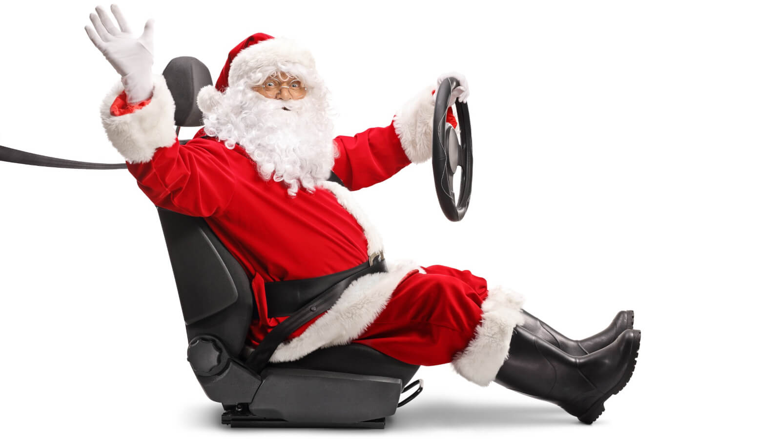 Nella foto c'è babbo natale con il suo classico vestito rosso e la barba bianca seduto su un sedile di auto con il volante retto dalla mano sinistra. Ha la cintura di sicurezza allacciata e saluta con la mano destra.