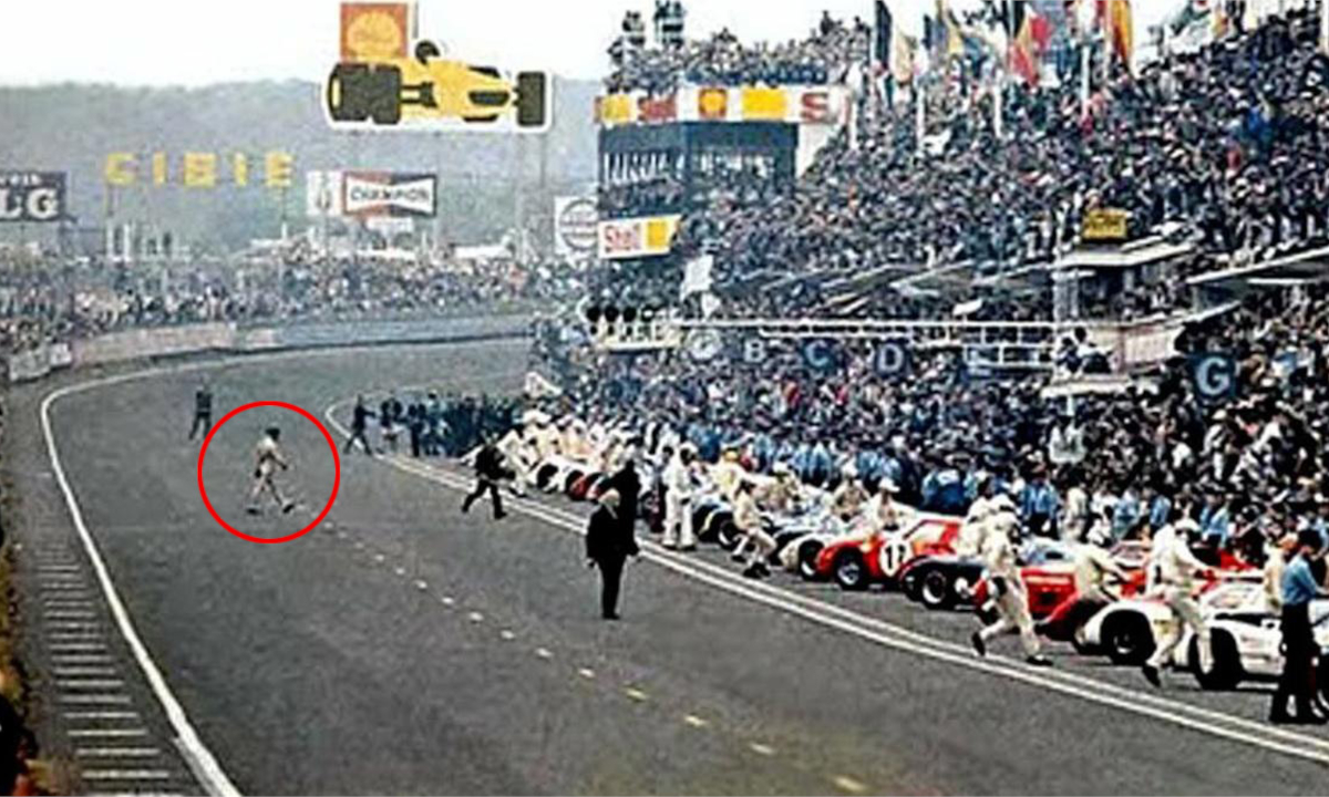 Jacky Ickx alla partenza della corsa delle 24 ore di Le Mans del 1969. Jacky, evidenziato da un cerchio rosso, passeggia verso la sua monoposto schierata dall'altro lato della pista. Sullo sfondo tribune piene di spettatori.